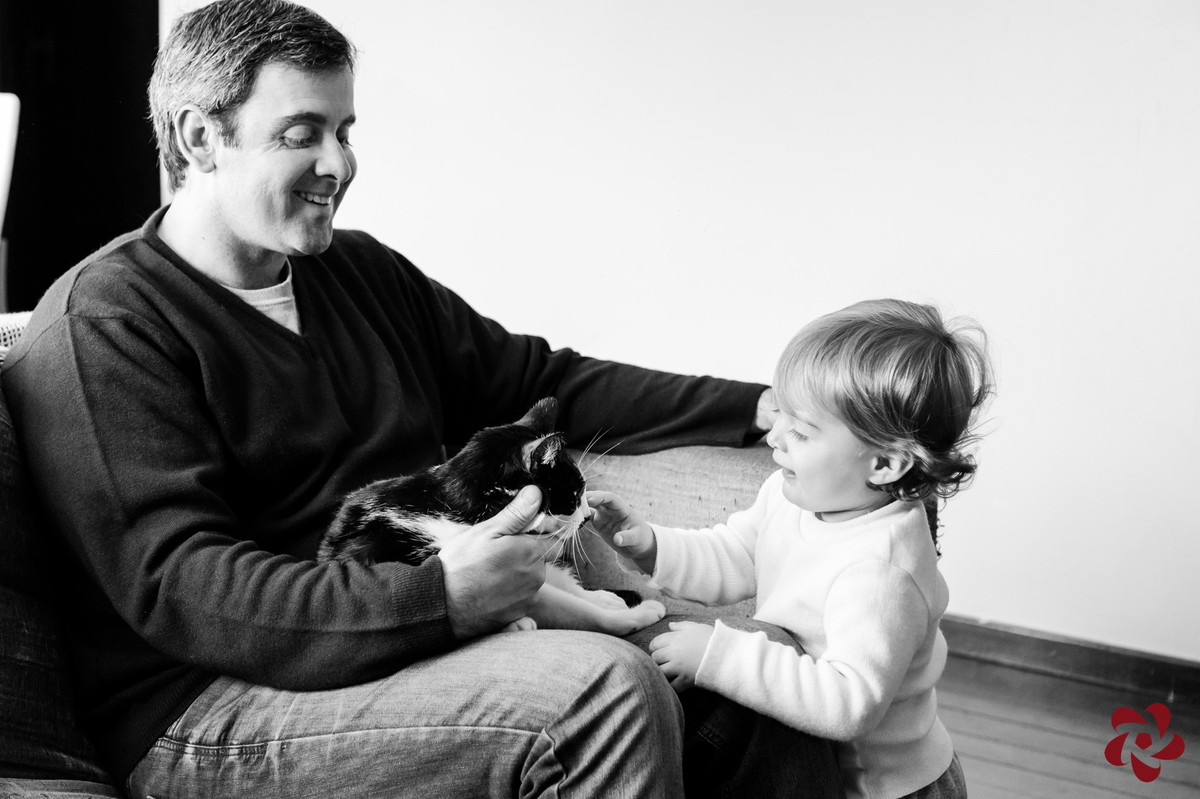 Rodrigo está no sofá com a gata no colo, que recebe a atenção do Otávio.