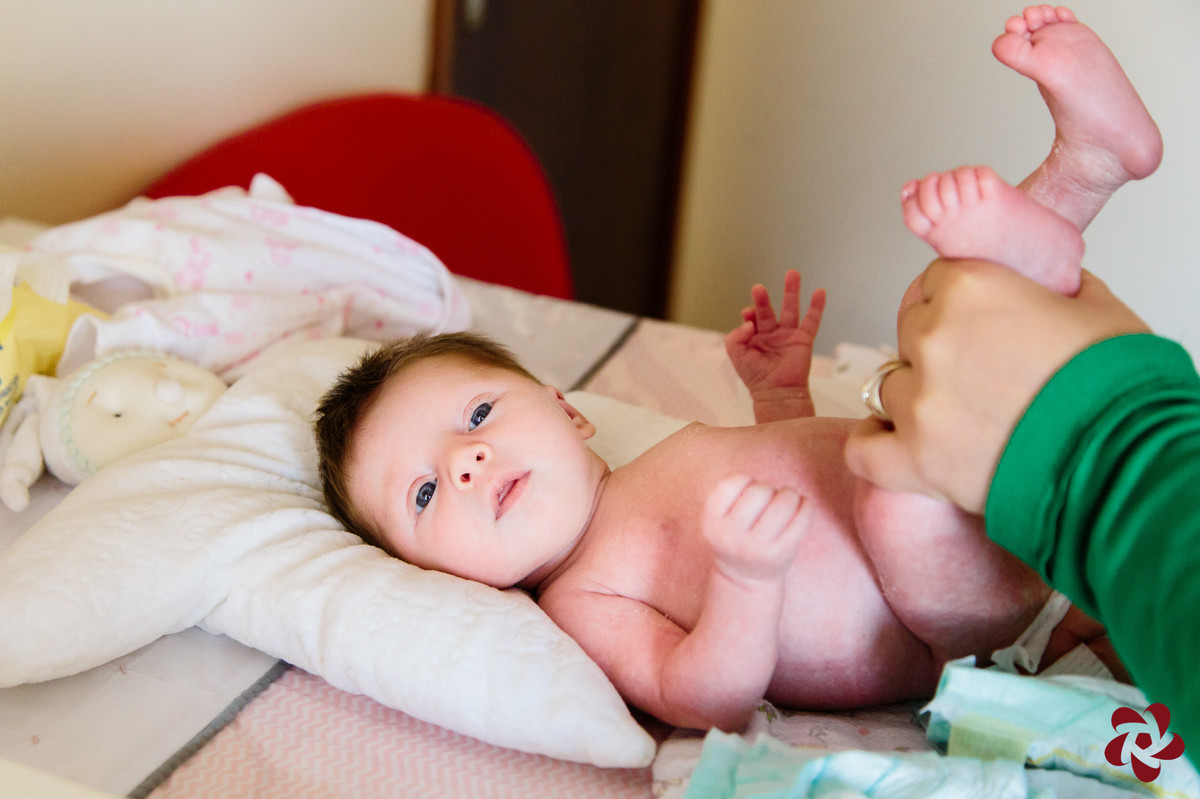 Júlia está deitada no seu trocador para bebê, como rosto virado para a câmera.