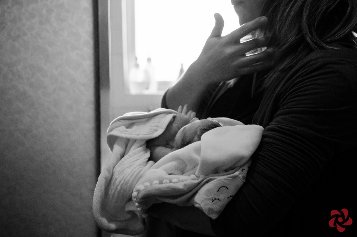 A mãe está com a filha no colo, enrolada em sua toalha de bebê.