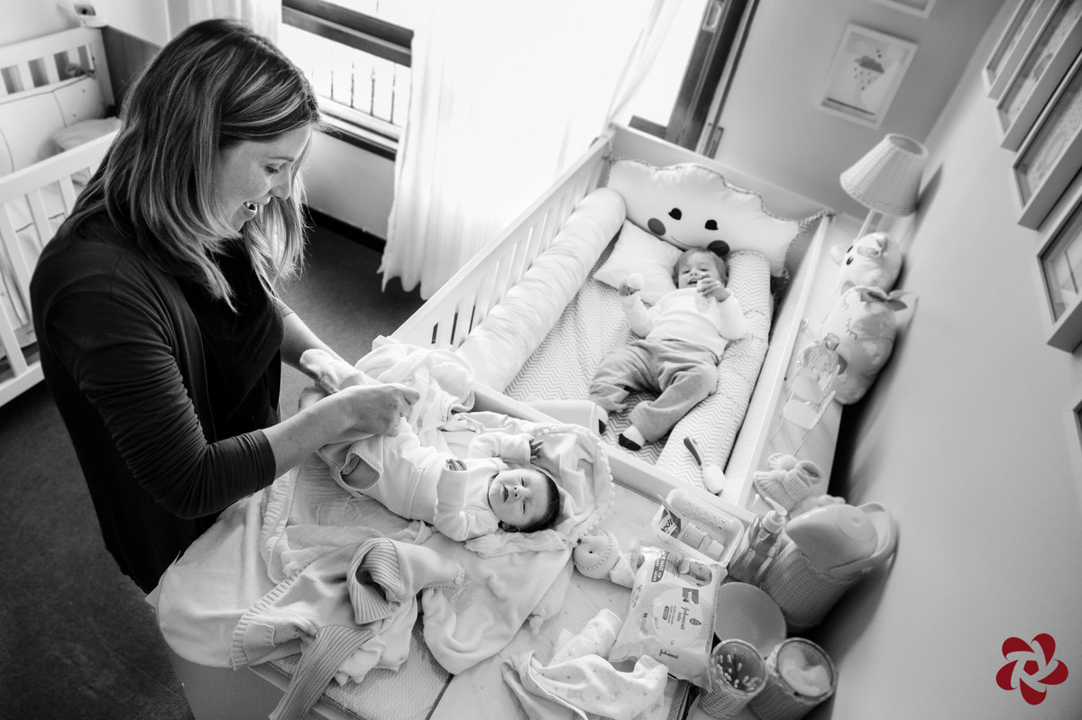 Enquanto a mãe está vestindo a filha recém chegada o irmão Otávio aproveita para brincar na cama da irmã.