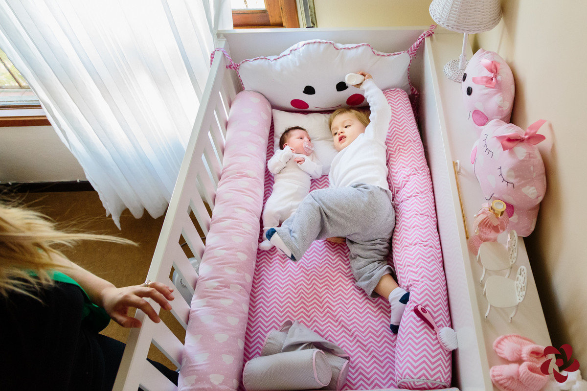 Júlia e Otávio estão deitados na caminha branca e rosa da irmã.