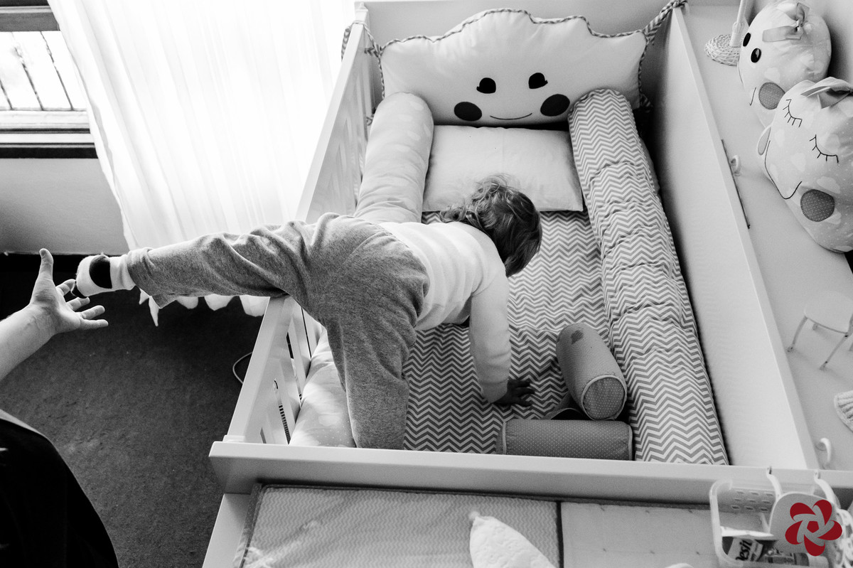 Otávio tenta sair da cama da irmã e a mãe coloca a mão para ele não cair.