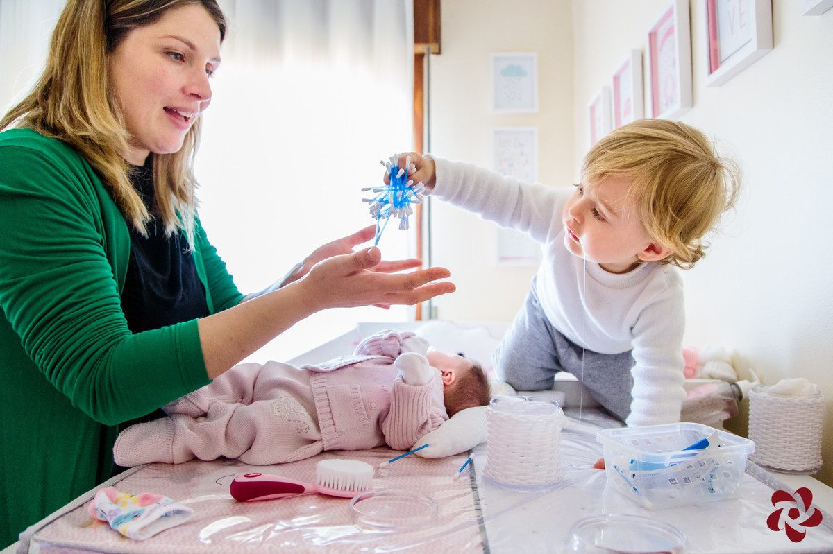Otávio sobe no trocador e fica ao lado da mãe e da irmã brincando com cotonetes.