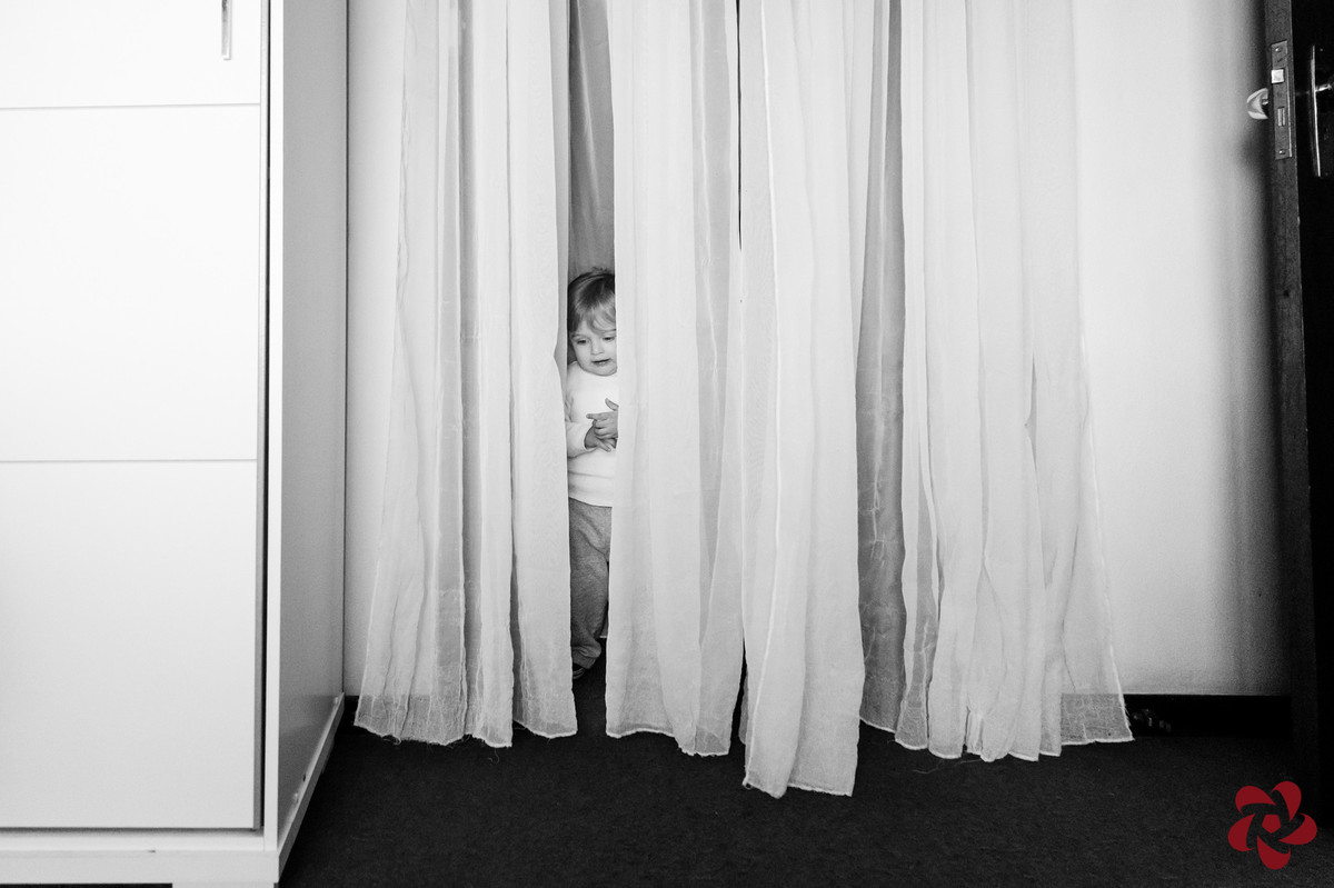 Otávio brinca de esconder nas cortinas brancas do closet do quarto dos pais.