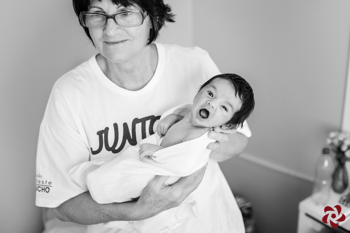 Foto em preto e branco da avó do Henrique está com ele no colo para dar banho e ele está com um sorriso feliz.