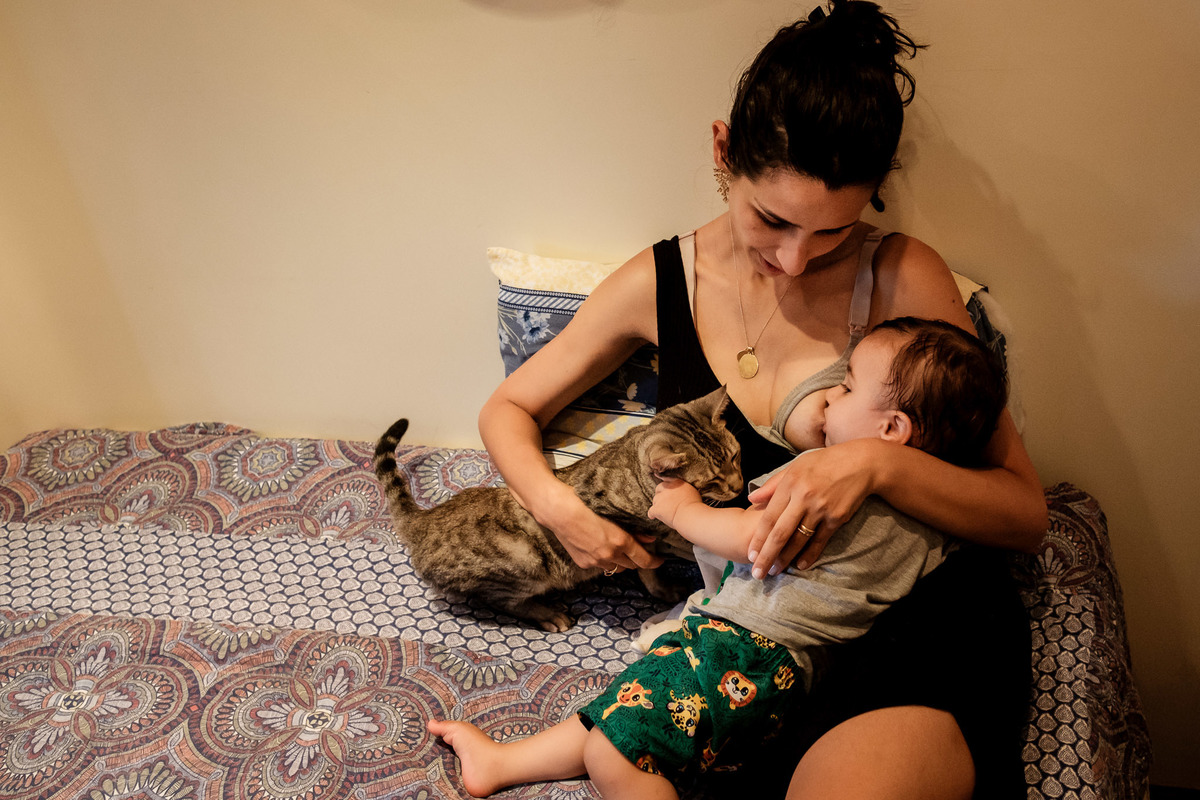 mãe amamentando o filho com o gato ao lado
