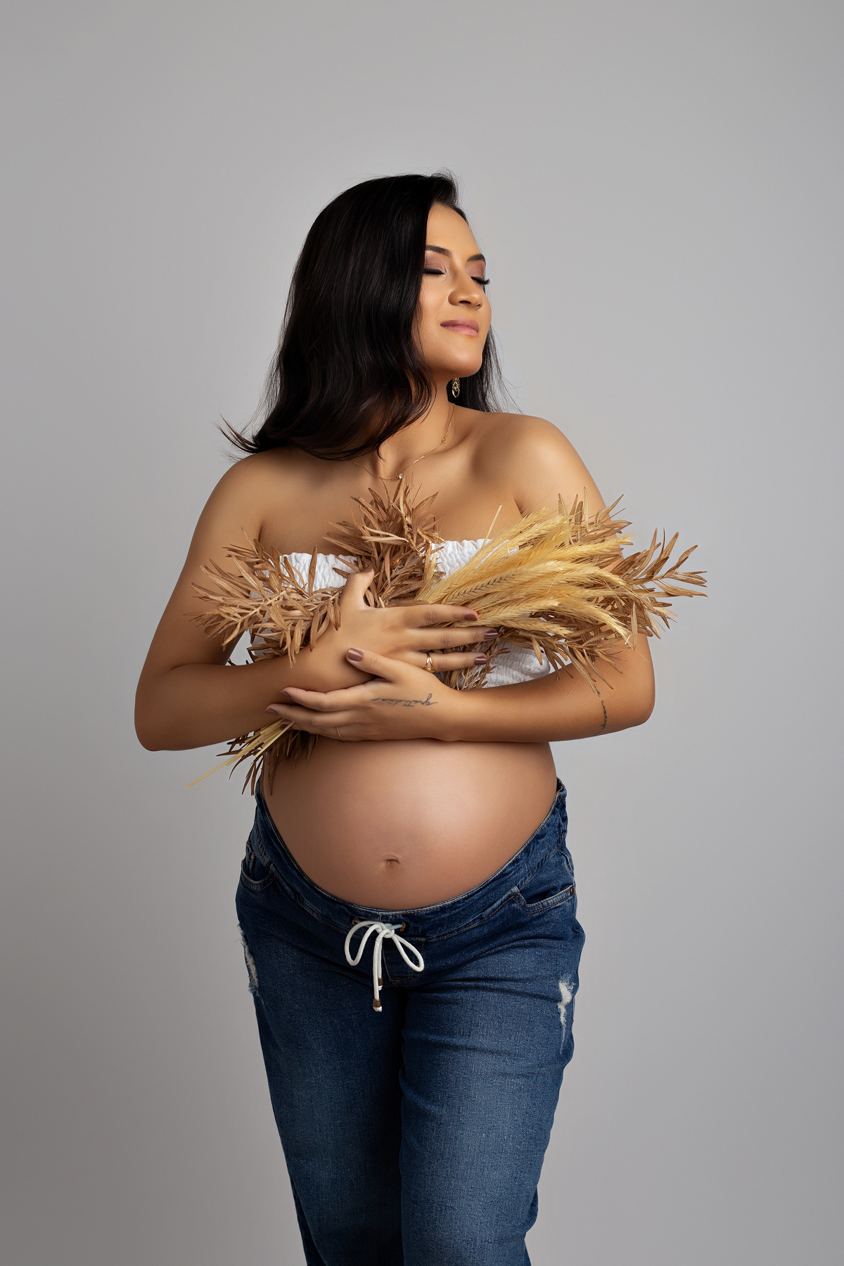 fotografia de gestante estudio fotografico de gestante ensaio fotografico de gestante look gestante calça jeans fotografia de gestante com folhas secas 