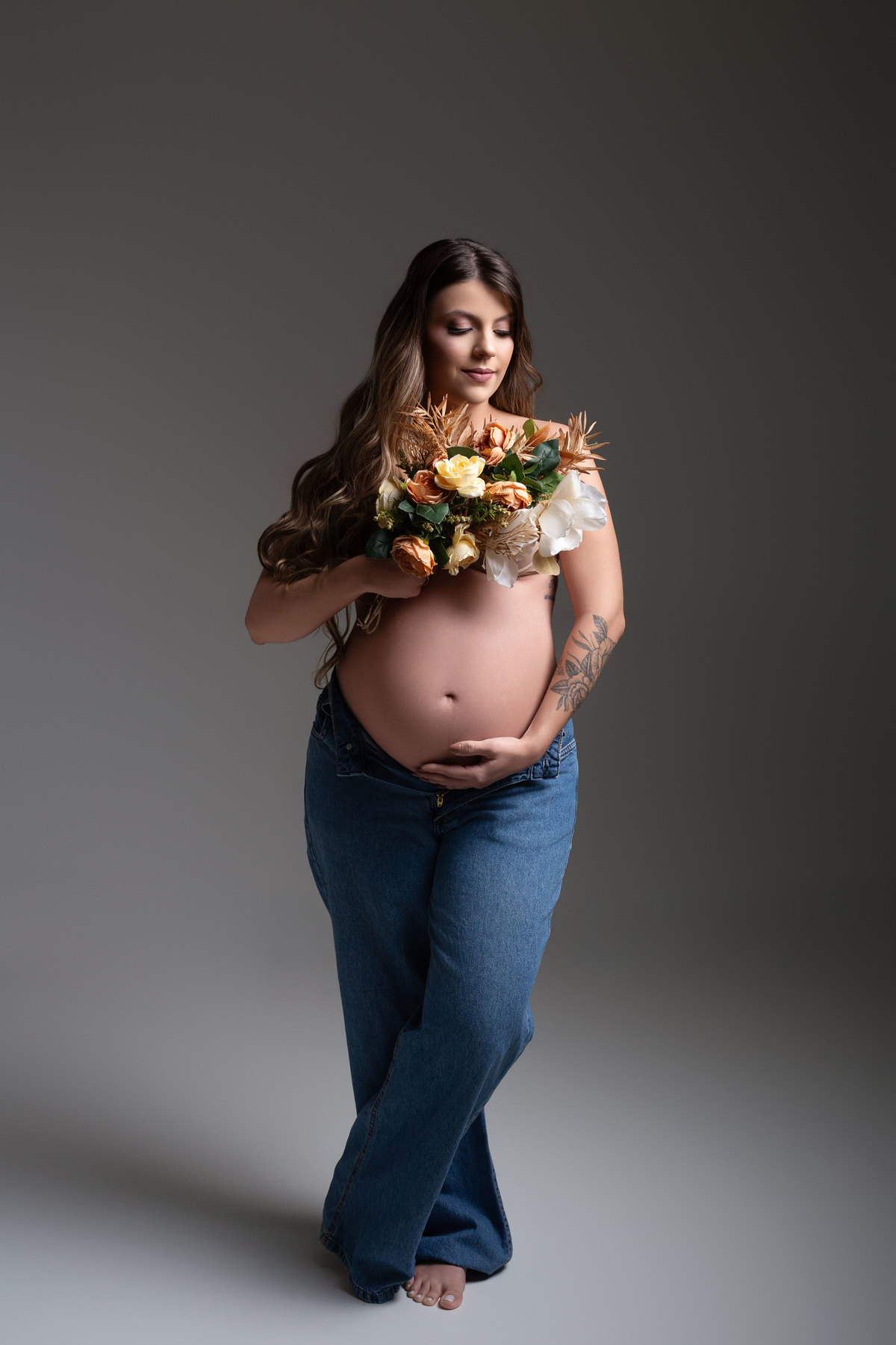 fotografia gestante romantica, ensaio gestante, fotografia gestante calça jeans, pose de gestante com flores 