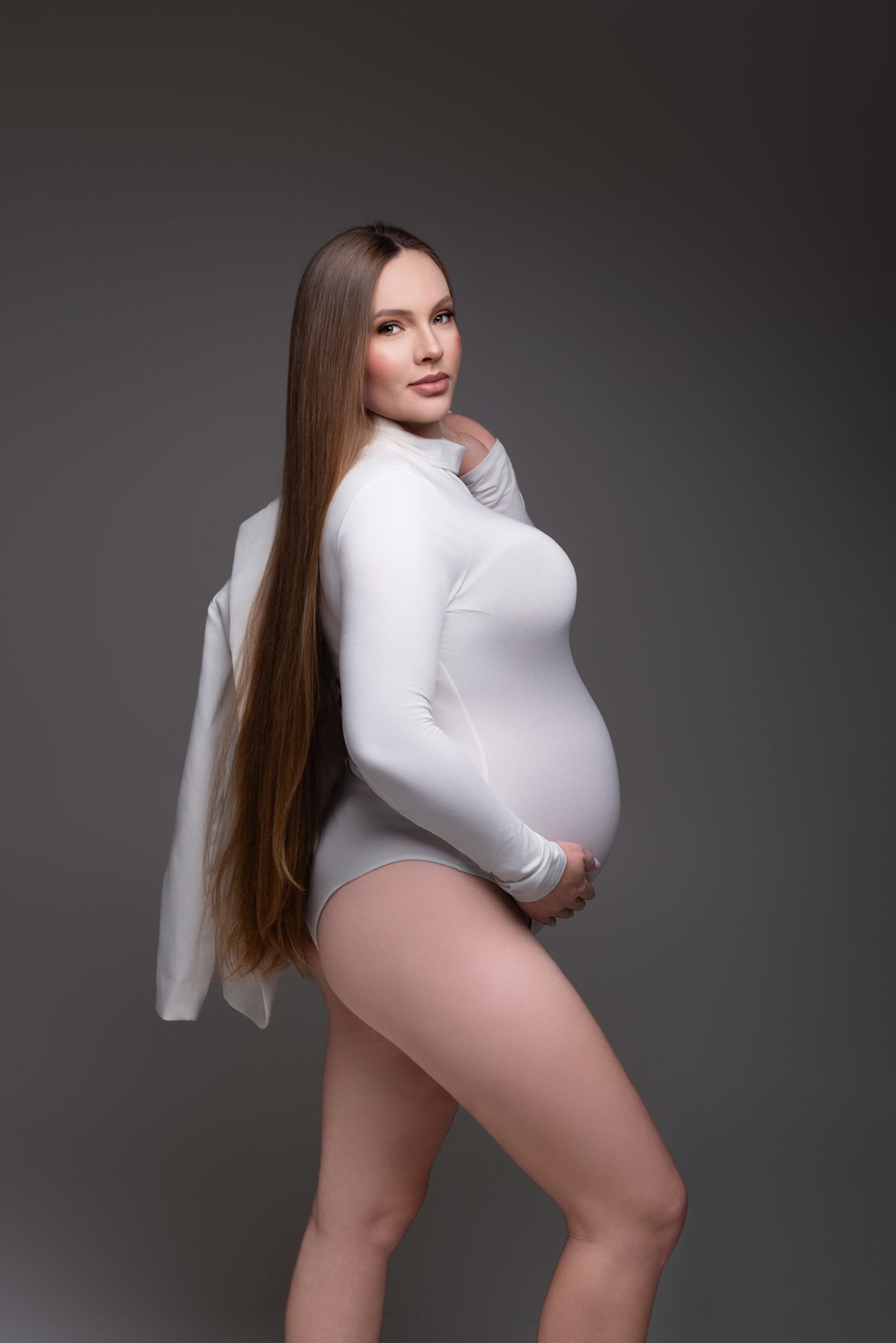 Fotografia de gestante em estúdio em Maringá PR, com estética minimalista e fundo neutro. Ensaio conduzido por fotógrafa especializada em gestante, em estúdio fotográfico para gestante, valorizando a maternidade com elegância.