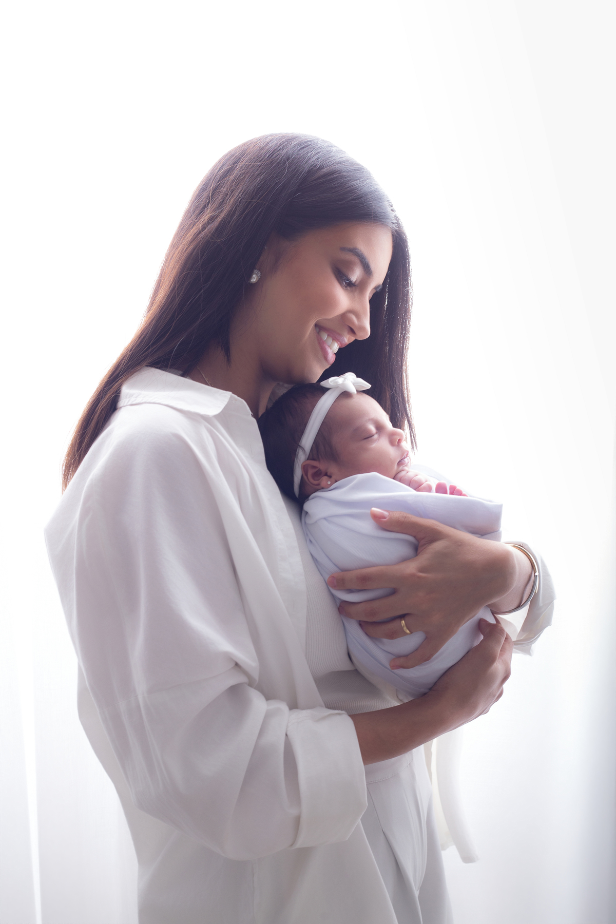 Recém-nascido dormindo tranquilamente no colo da mãe durante ensaio newborn lifestyle.