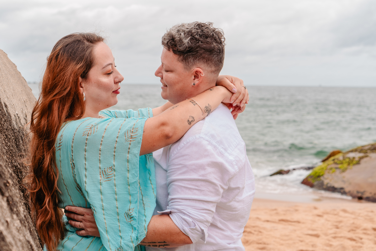 Olhares apaixonados – O reflexo do mar nos olhos do casal transmite a profundidade desse amor. O pós-wedding na praia traduz cumplicidade e entrega. #EnsaioLGBTQIA+