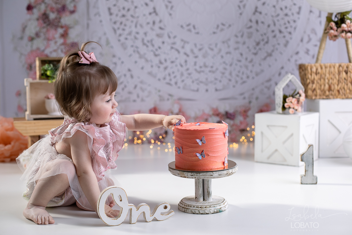 ensaio-fotografico-da-hora-do-bolo-esmagando-o-bolo-smash-the-cake-one-bebe-de-um-ano-acompanhamento-fotografico-de-bebes-fotografa-especializada-em-criancas-em-barbacena-isabela-lobato-fotografia-fundo-fotografico-de-smash-the-cake-cenario-fotografico