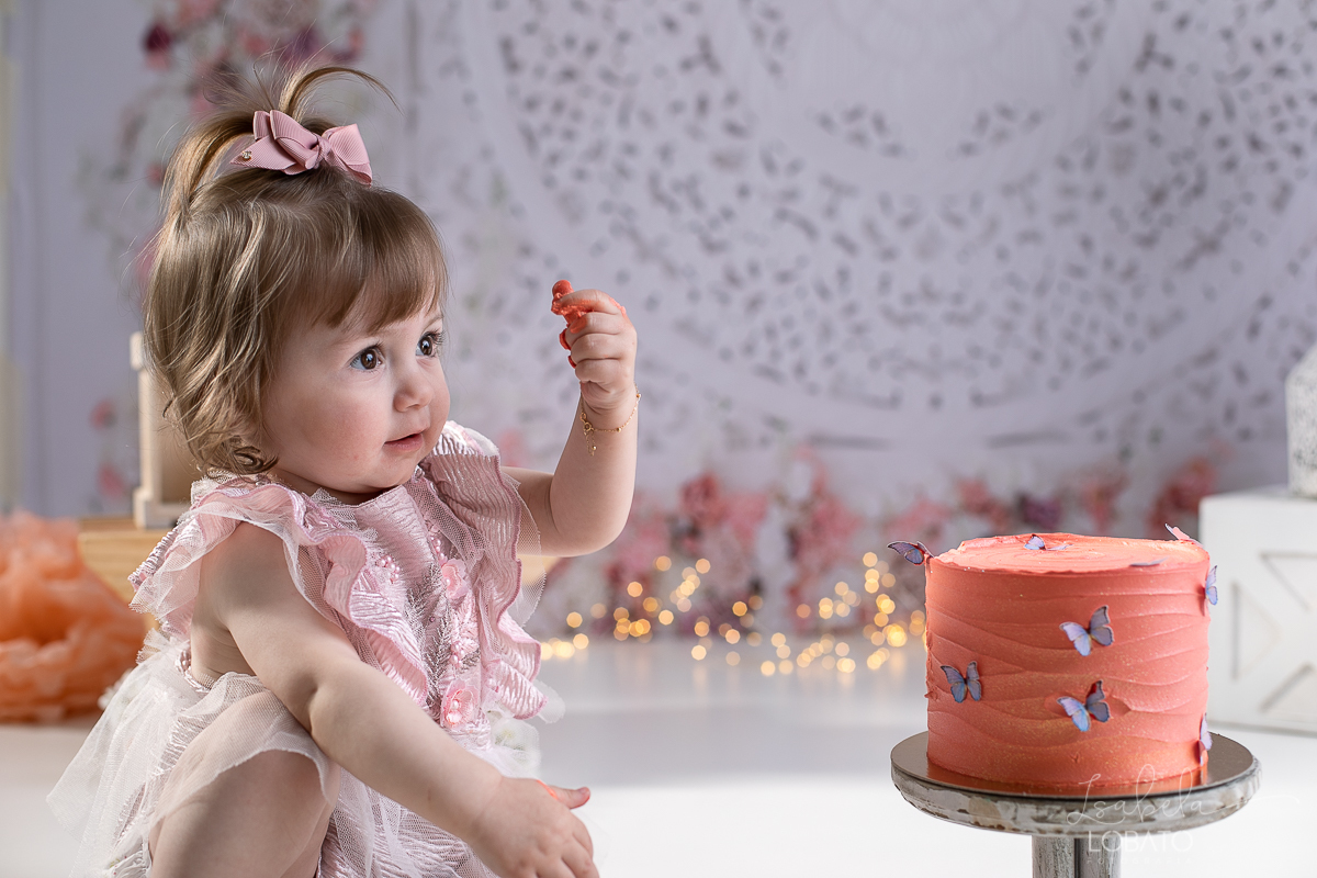ensaio-fotografico-da-hora-do-bolo-esmagando-o-bolo-smash-the-cake-one-bebe-de-um-ano-acompanhamento-fotografico-de-bebes-fotografa-especializada-em-criancas-em-barbacena-isabela-lobato-fotografia-fundo-fotografico-de-smash-the-cake-cenario-fotografico
