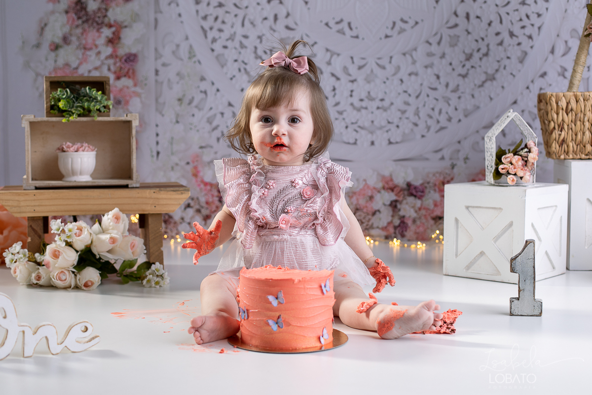 ensaio-fotografico-da-hora-do-bolo-esmagando-o-bolo-smash-the-cake-one-bebe-de-um-ano-acompanhamento-fotografico-de-bebes-fotografa-especializada-em-criancas-em-barbacena-isabela-lobato-fotografia-fundo-fotografico-de-smash-the-cake-cenario-fotografico