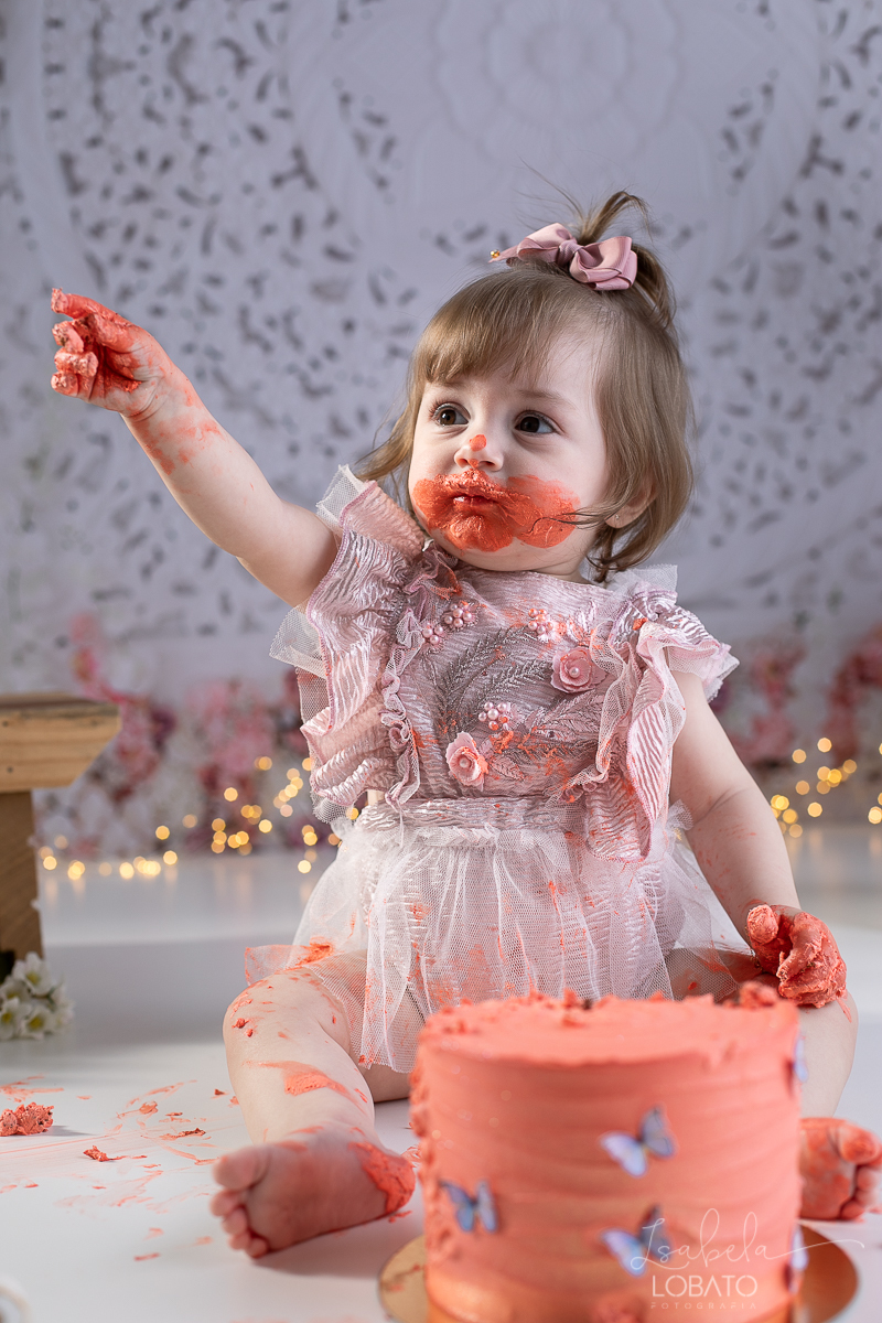 ensaio-fotografico-da-hora-do-bolo-esmagando-o-bolo-smash-the-cake-one-bebe-de-um-ano-acompanhamento-fotografico-de-bebes-fotografa-especializada-em-criancas-em-barbacena-isabela-lobato-fotografia-fundo-fotografico-de-smash-the-cake-cenario-fotografico