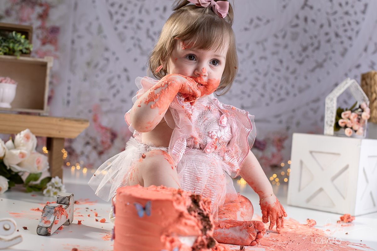 ensaio-fotografico-da-hora-do-bolo-esmagando-o-bolo-smash-the-cake-one-bebe-de-um-ano-acompanhamento-fotografico-de-bebes-fotografa-especializada-em-criancas-em-barbacena-isabela-lobato-fotografia-fundo-fotografico-de-smash-the-cake-cenario-fotografico