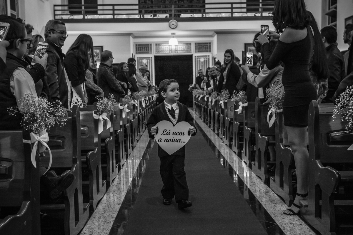 pajem caminhando pelo corredor central da igreja São Benedito com a plaquinha na mão