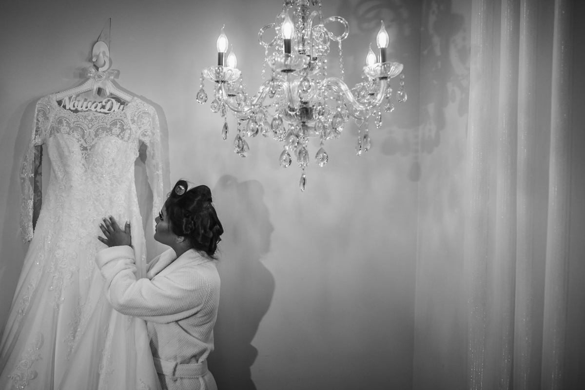 Noiva conferindo os detalhes com o  vestido pendurado