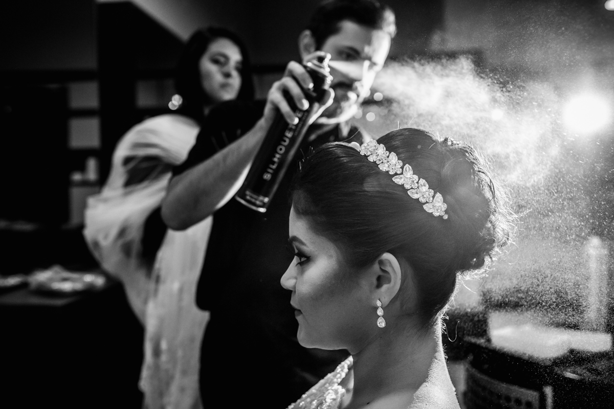 cabeleireiro com o spray fixador no cabelo dando os últimos retoques e finalizando o penteado