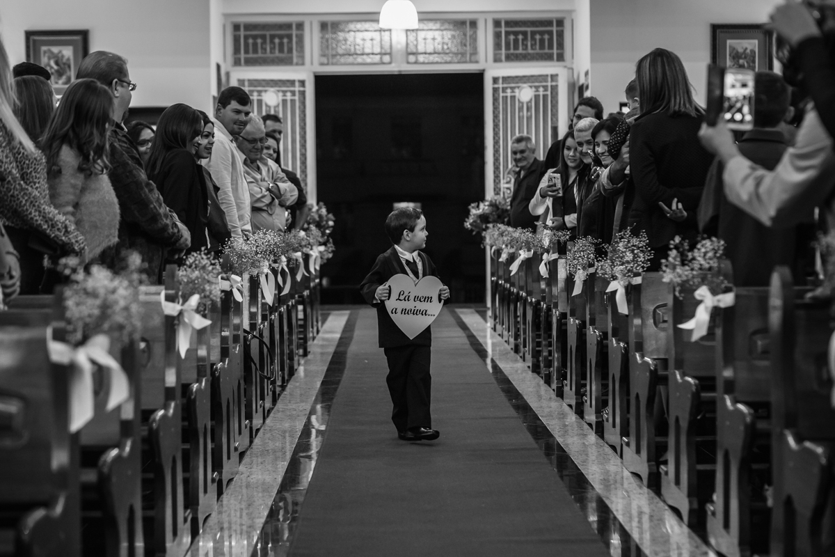 pajem carregando a plaquinha pelo corredor da Igreja São Benedito