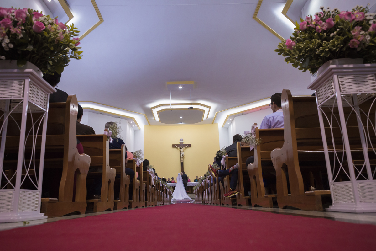 vista do corredor central da igreja com os noivos ao fundo no altar
