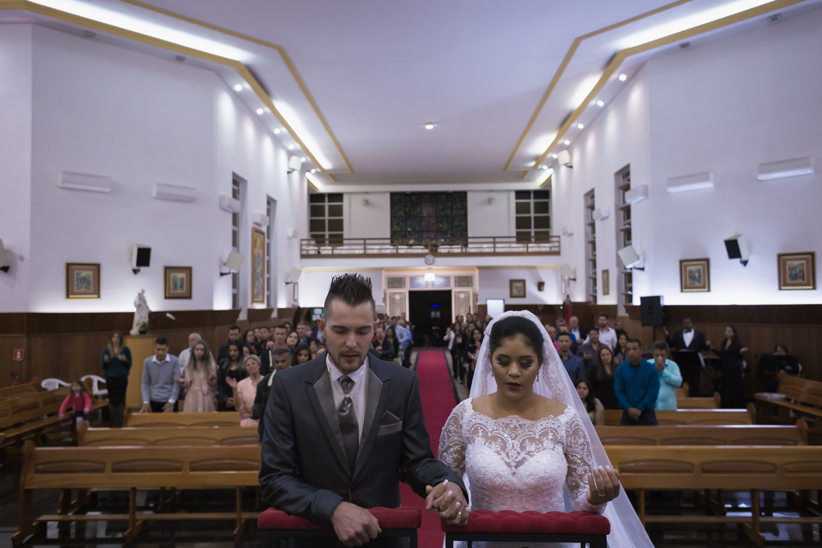 noivos ajoelhados e rezando no altar após tomarem o corpo de cristo