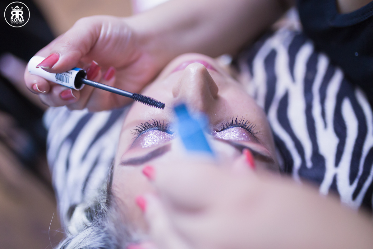 a maquiadora passando mascara de cilios na noiva