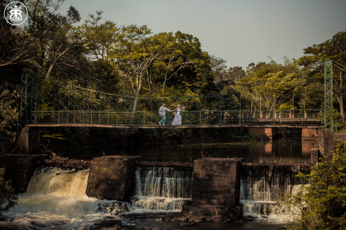 Casal passeando em uma ponte estaiada antiga sobre uma linda cachoeira