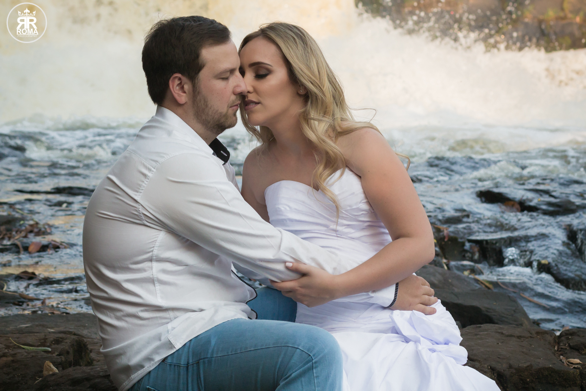 noiva beijando o noivo próximos a cachoeira