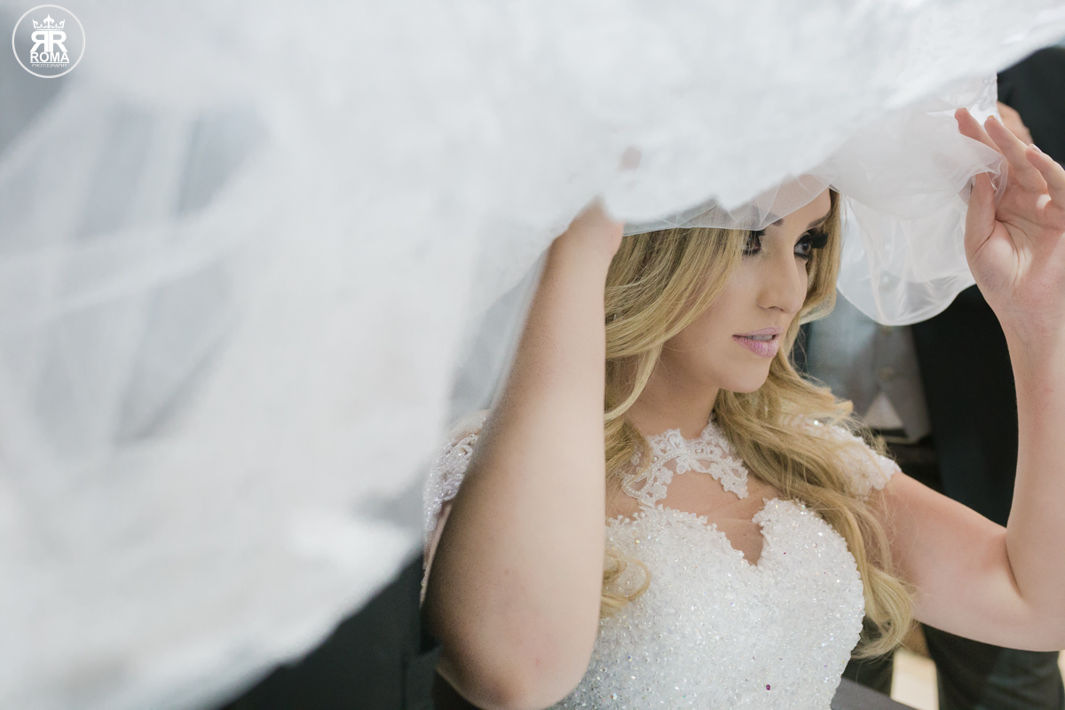 a noiva segurando seu véu e  se olhando no espelho achando se linda 