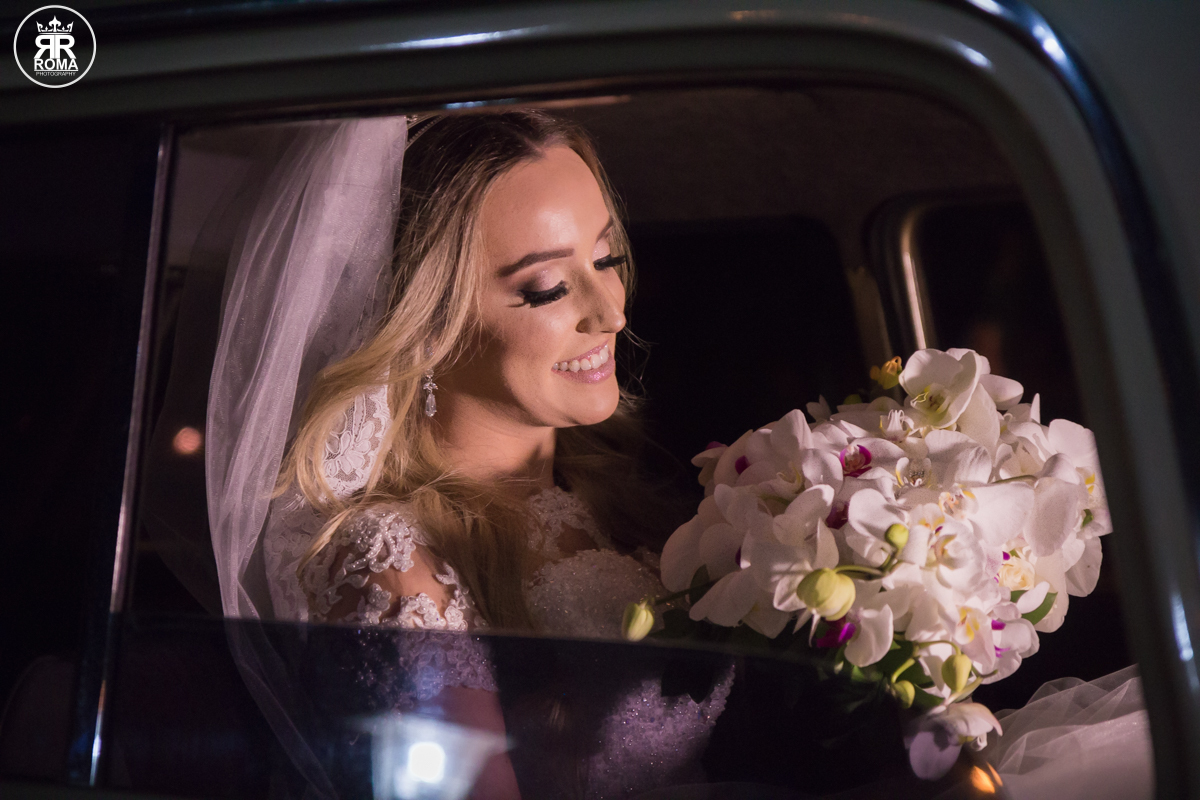 noiva feliz esperando a hora de sua entrada dentro do carro olhando seu buque
