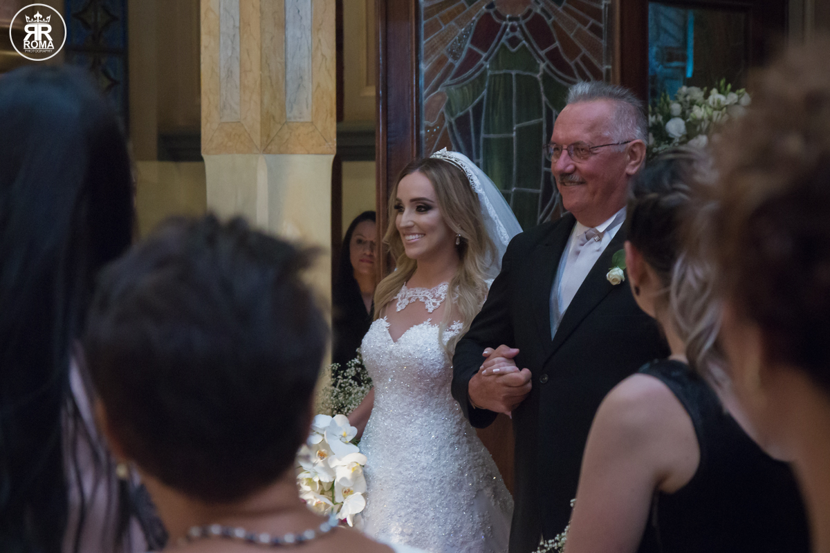 noiva sorrindo junto de seu pai no tapete vermelho