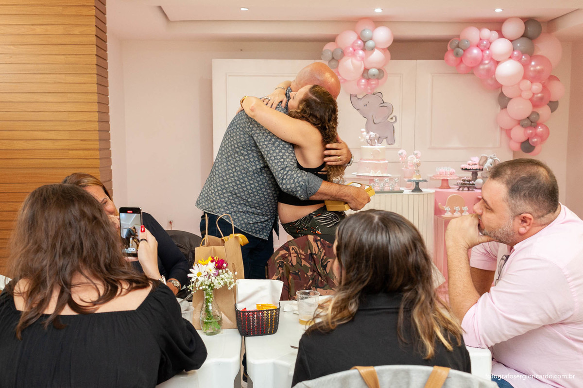 foto da gestante convidando a amigo para ser padrinho durante chá de fralda com tema dunbo baby na cor rosa