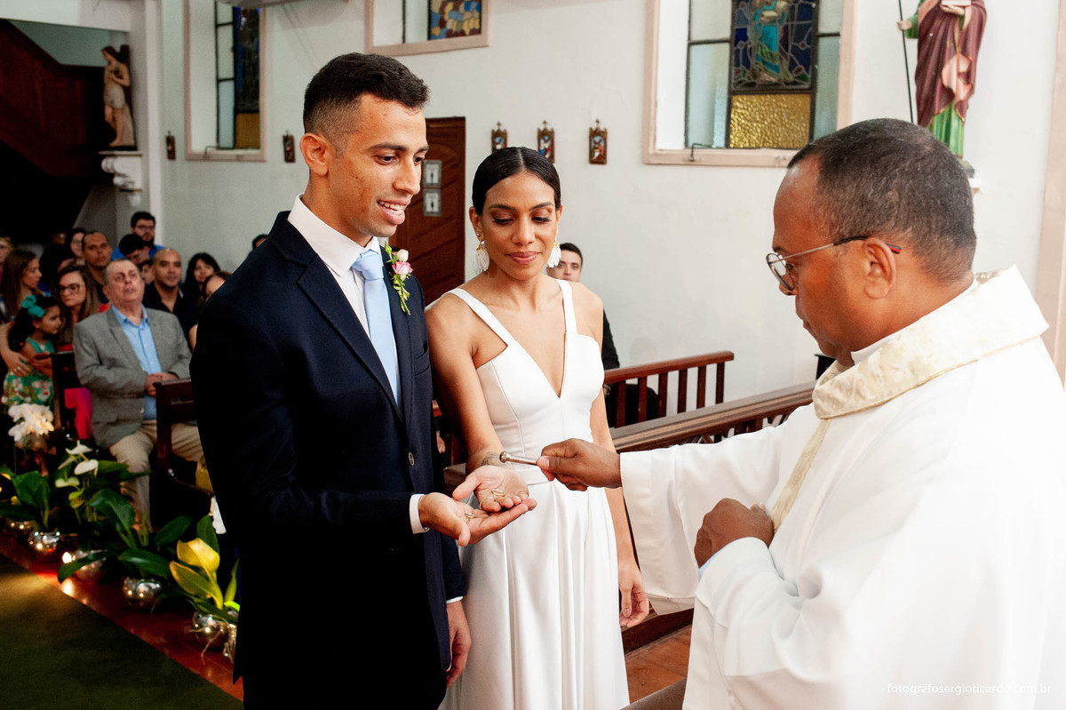 imagem dos noivos durante o casamento e a benção das alianças na capela santa ignez no bairro da gávea no rio de janeiro
