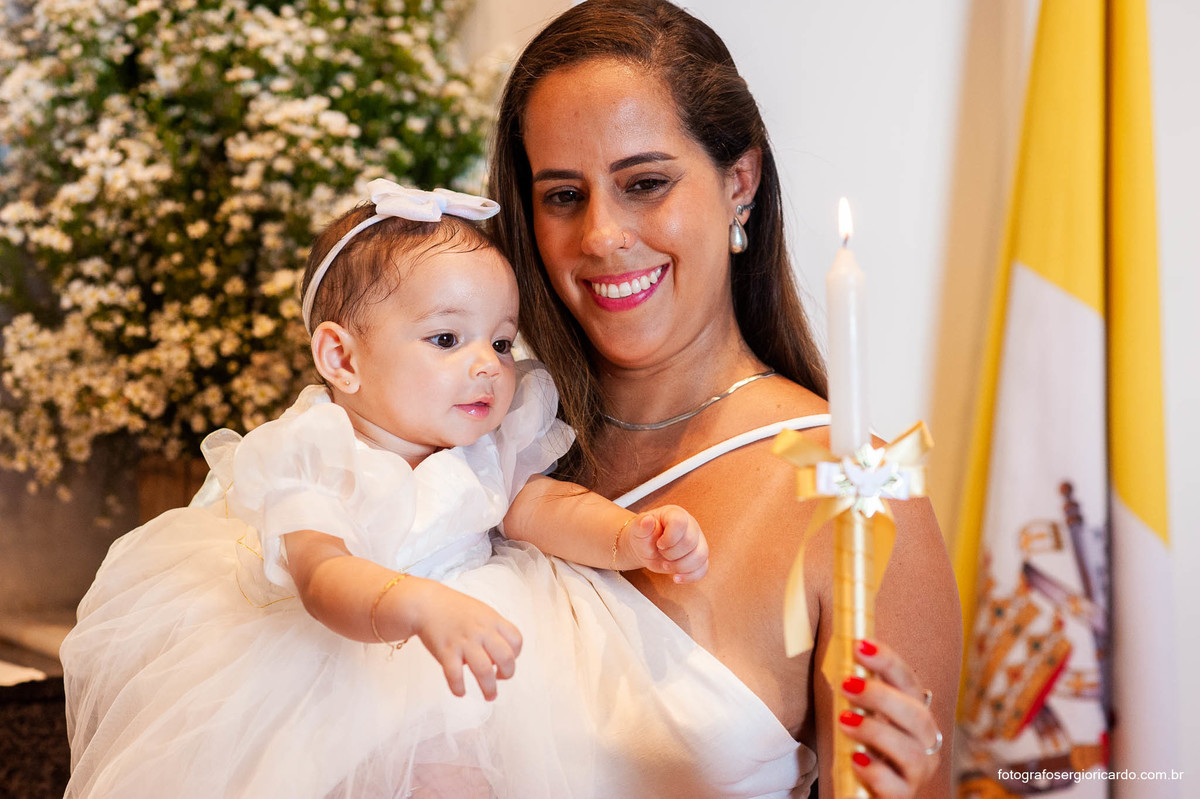 Fotografia da madrinha com criança na cerimônia de batismo na Capela de Nossa Senhora Aparecida no Cristo Redentor localizado no Morro do Corcovado no Rio de Janeiro