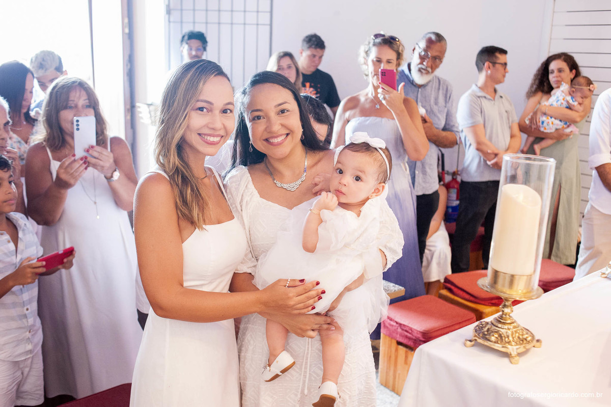 Fotografia da mãe e madrinha com criança na cerimônia de batismo na Capela de Nossa Senhora Aparecida no Cristo Redentor localizado no Morro do Corcovado no Rio de Janeiro