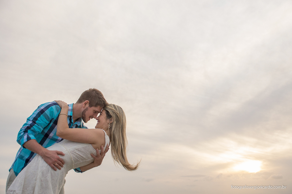 Foto dos noivos namorando ao entardecer no pier da praia de Manguinhos em Búzios no Rio de Janeiro