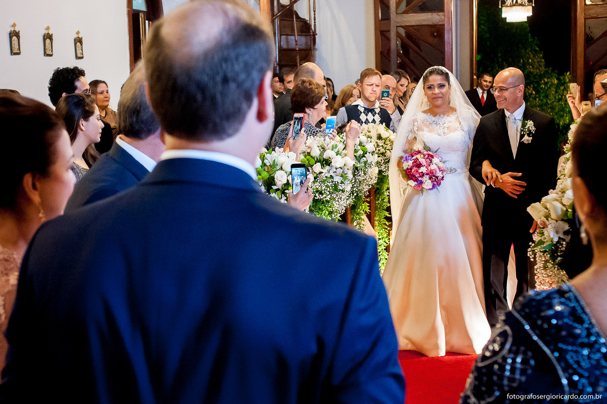 noivo vendo a noiva entrar de vestido branco na igreja