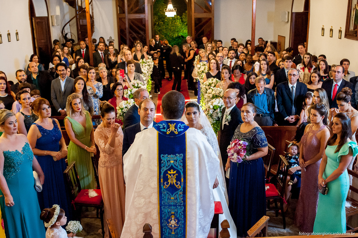 padre celebrando casamento com os noivos no altar