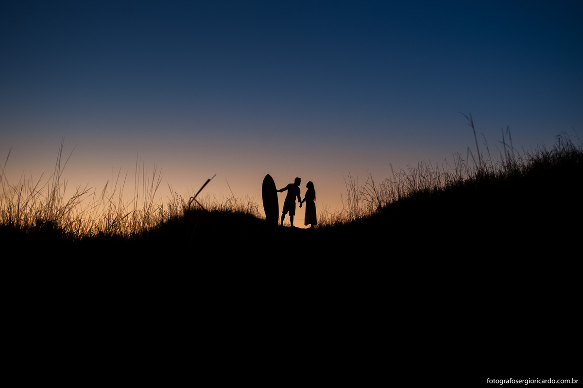 Casal de mãos dadas durante o amanhecer na praia do Secreto.