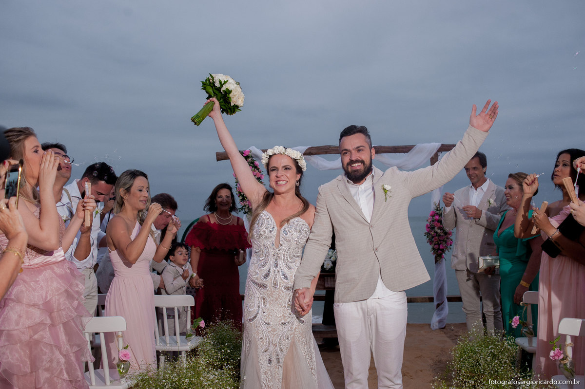 foto dos noivos felizes saindo da cerimônia de casamento pé na areia em búzios