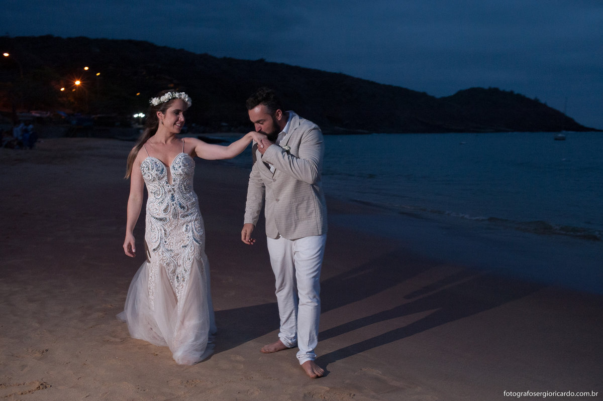 foto do noivo beijando a mão da noiva na praia de joão fernandes em búzios
