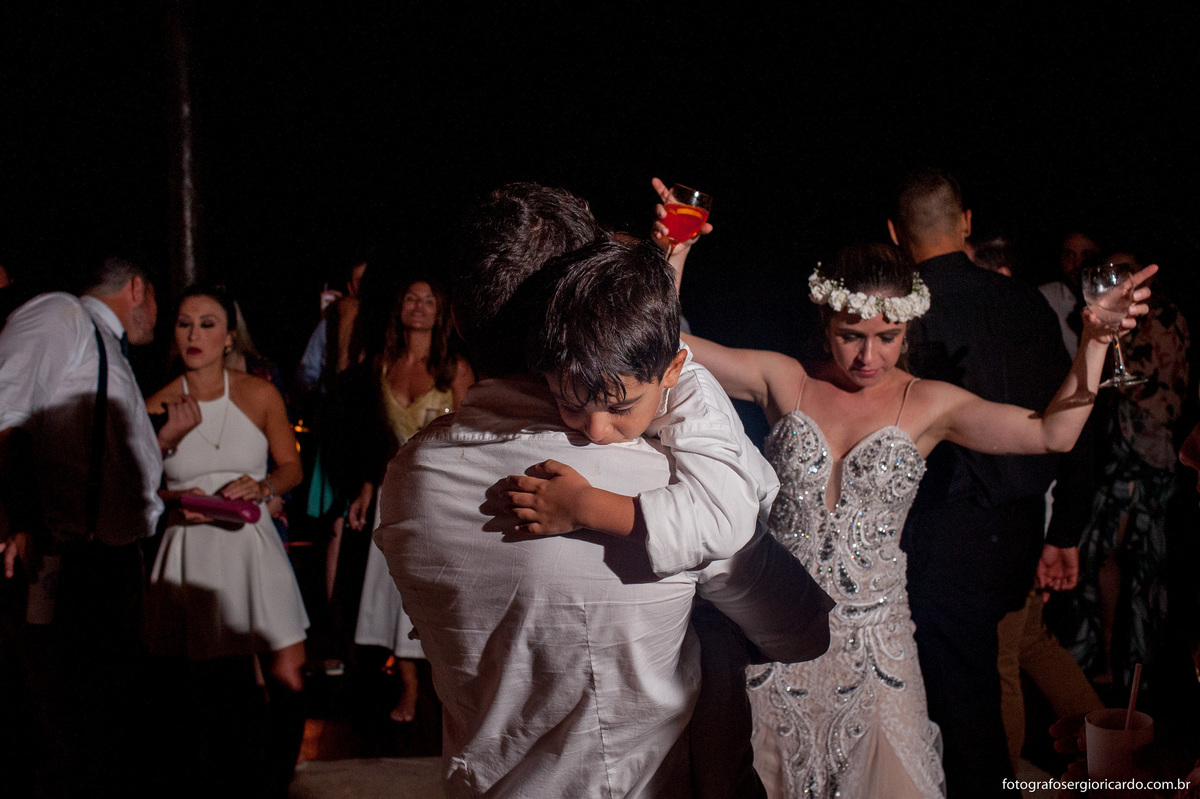 filho dos noivos dormindo nos braços durante a festa de casamento no club la plage