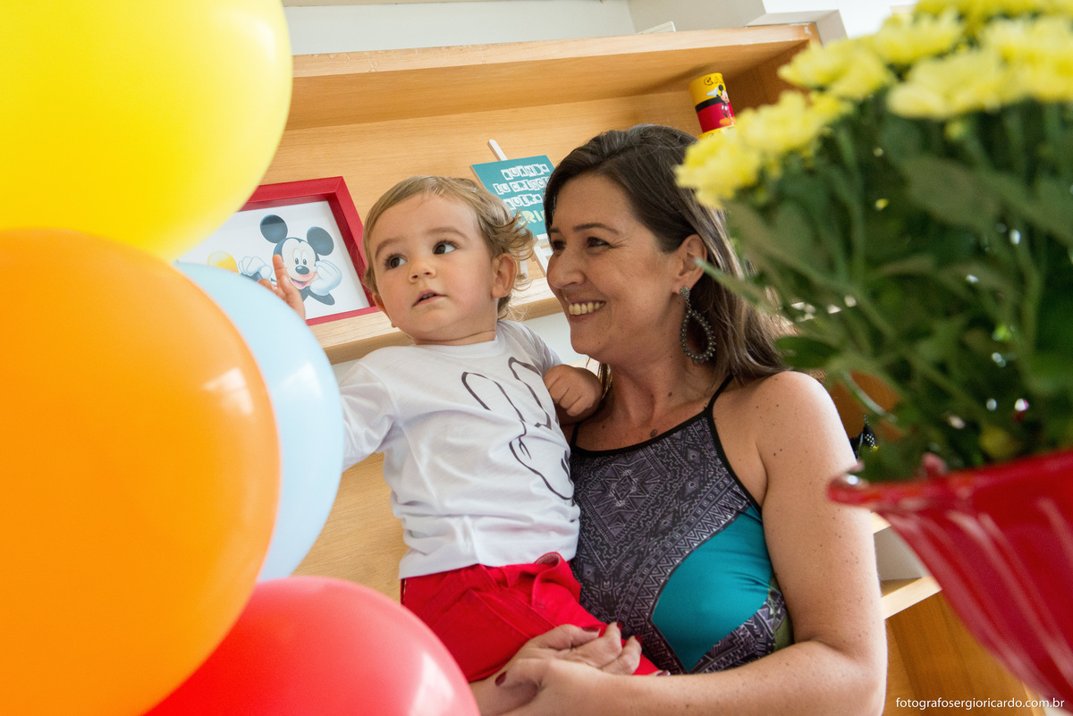 mãe com o filho no colo em festa de criança