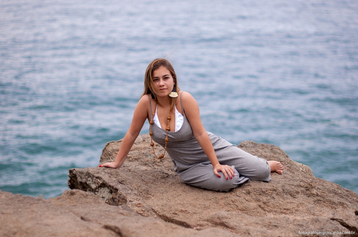 retrato de debutante sentada na pedra na praia da joatinga