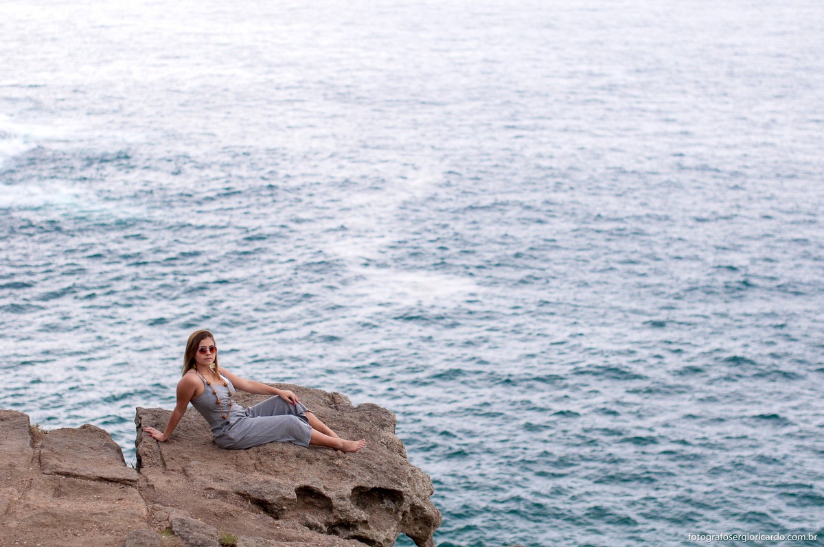 foto da debutante na pedra em paria da joatinga e com mar ao fundo