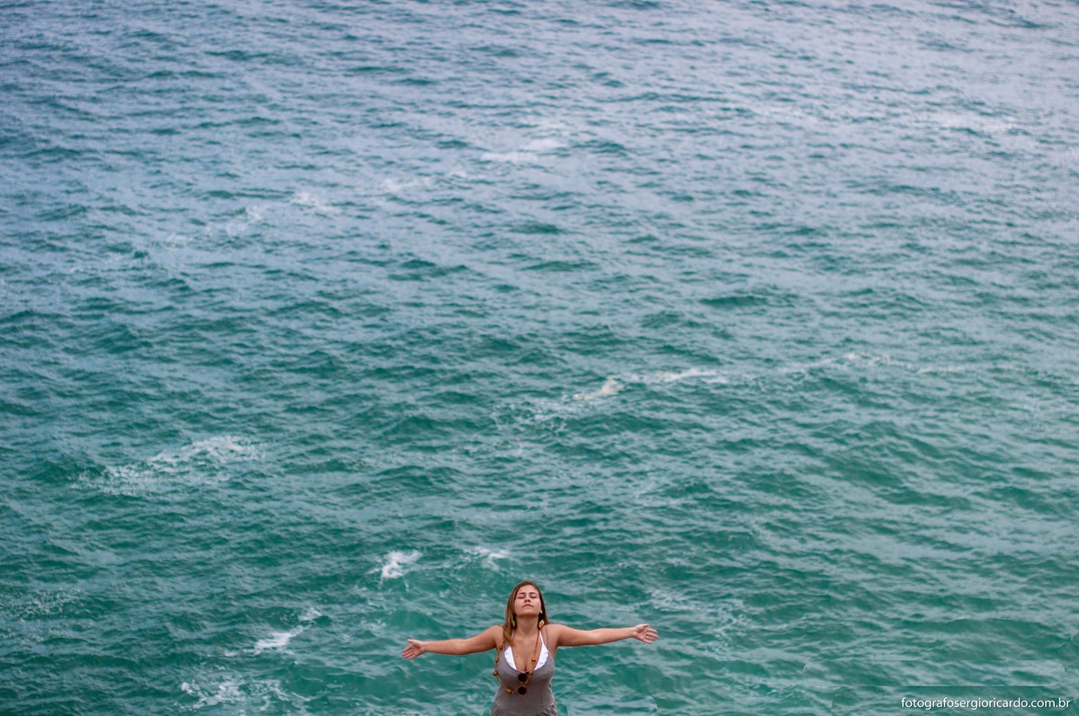 foto de debutante de braços abertos com mar ao fundo na praia da joatinga