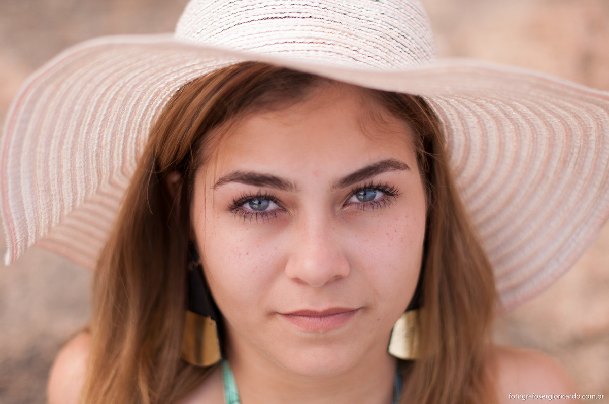 retrato da debutante com olhos azuis e chapéu na praia da joatinga
