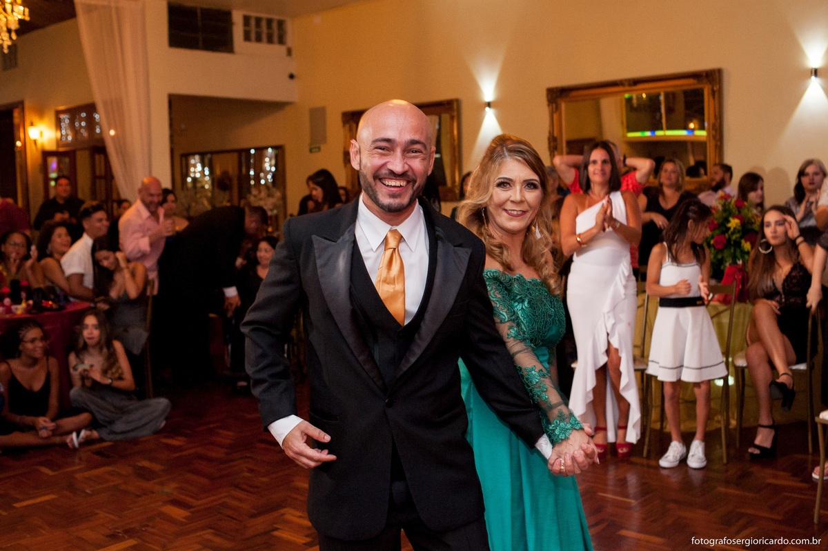 imagem dos pais da debutante pelo salão da casa de festas