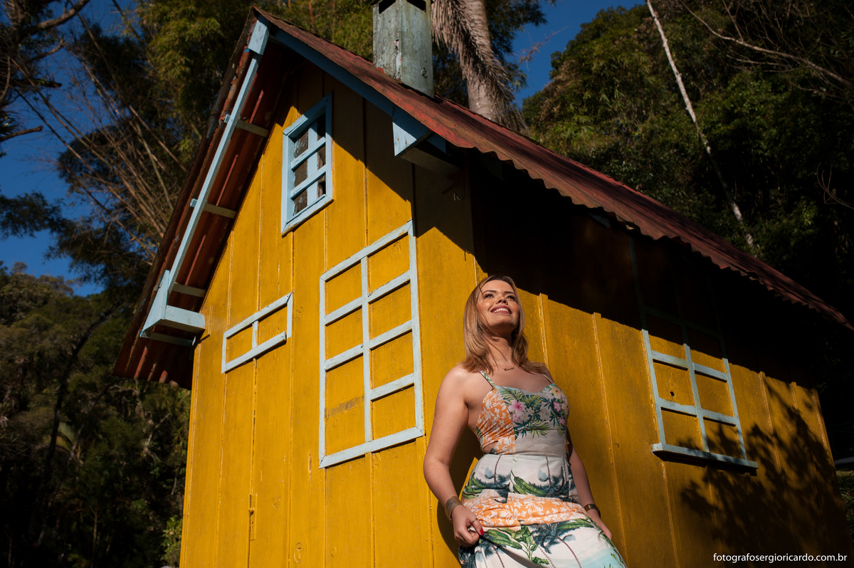ensaio de aniversário de 30 anos com a pessoa sorrindo encostada numa casa amarela